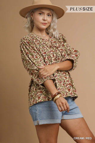 Woman wearing a floral blouse, denim shorts, and a hat on a beige background