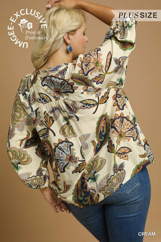 Woman wearing a plus-size cream blouse with butterfly pattern on a beige background