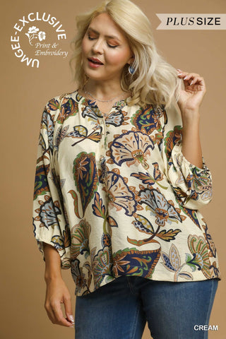Woman wearing a plus-size cream floral blouse with text indicating exclusivity and size availability.