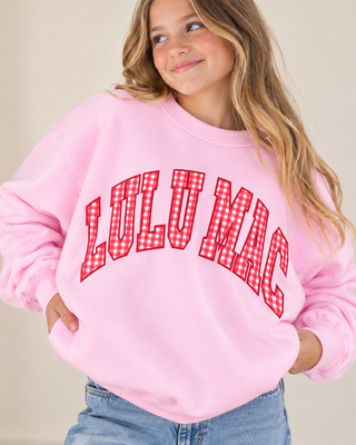 a pink crewneck sweatshirt with 'LULU MAC' printed in red and white gingham lettering