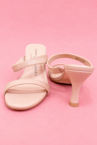 Pair of pink high-heeled sandals on a pink background