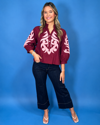 Rich ruby cotton top with blush embroidered appliqué, ruffle neckline, three-quarter balloon sleeves, and button placket.