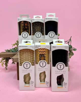 Packaging of Teleties hair care products on a pink background