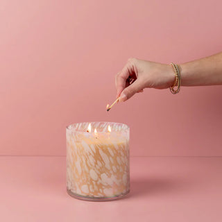 Hand lighting a candle with a pink background