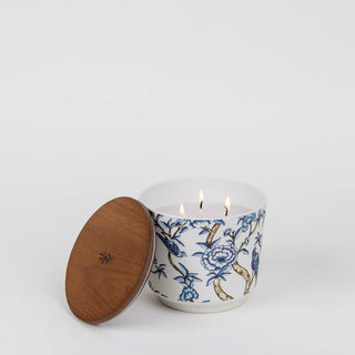 Candle in a decorative container with floral design on a white background