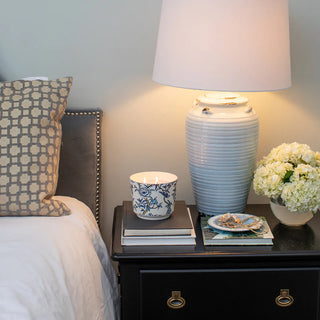 Nighstand with decorative items including a lamp, books, and a vase.