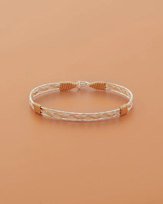 Braided bracelet with gold and silver accents on a beige background