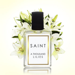 Perfume bottle labeled 'SAINT A Thousand Lilies' surrounded by white lilies on a light background