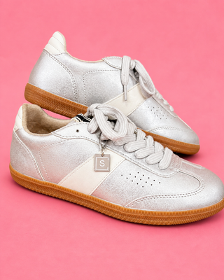 White sneakers with brown soles on a pink background