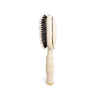 Beige hairbrush with black bristles on a white background