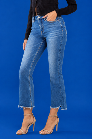 A model wearing medium-wash blue cropped flare jeans with a raw frayed hem