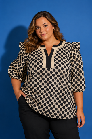 Woman wearing a polka dot blouse against a blue background