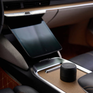 Car cup holder with a tablet stand and small black device on a wooden surface