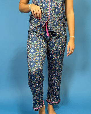 A person wearing a matching floral pajama set with a dark navy base and small multicolored flowers, featuring pink trim an