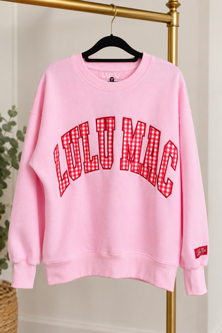 a pink crewneck sweatshirt with 'LULU MAC' printed in red and white gingham lettering
