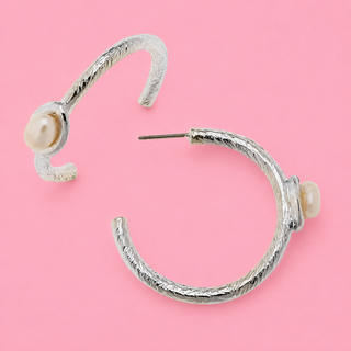 Silver hoop earrings with pearl accents on a pink background