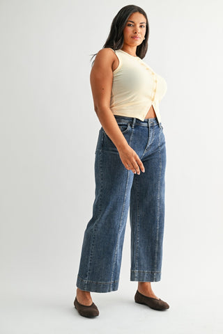 Woman wearing a yellow top and blue jeans on a white background