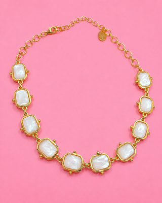 Gold necklace with white stones on a pink background