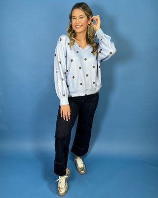 Light blue textured polka dot V-neck top with contrasting brown dots, relaxed drop shoulders, long sleeves