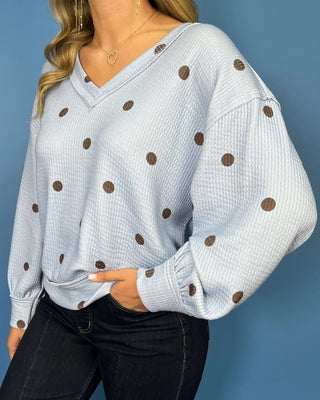 Light blue textured polka dot V-neck top with contrasting brown dots, relaxed drop shoulders, long sleeves