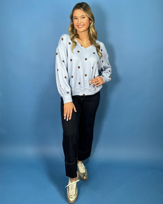 Light blue textured polka dot V-neck top with contrasting brown dots, relaxed drop shoulders, long sleeves