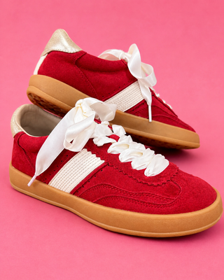 Red sneakers with white laces on a pink background