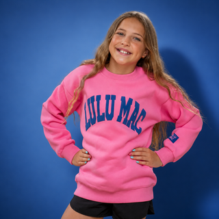 Girl wearing a pink sweatshirt with 'LULU MAC' text against a blue background