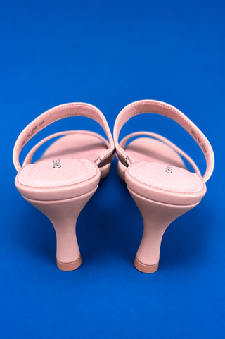 A pair of light pink slingback high-heeled sandals shown from the back, featuring a low kitten heel and a small metallic log