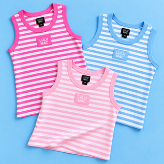 Three sleeveless striped tank tops arranged in an overlapping flat-lay on a light blue background. The top left tank is pink and white striped with a pink trim and a pink 'LULU MAC' patch.