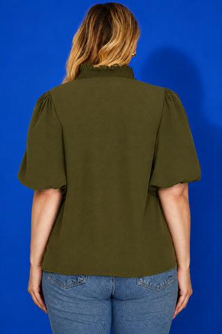 Green blouse with ruffled neckline on a blue background