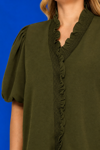 Green blouse with ruffled neckline on a blue background