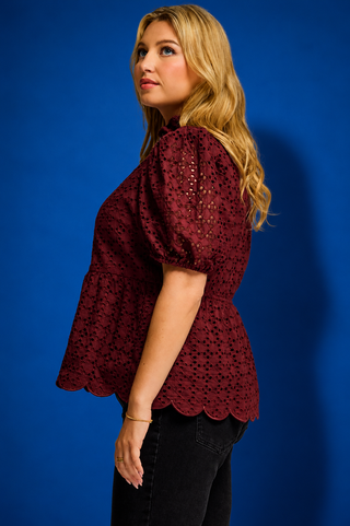  a burgundy eyelet lace short-sleeve blouse with puff sleeves and a scalloped hem