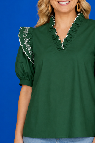Green puff-sleeve blouse with light-wash jeans.