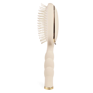 Beige hairbrush with gold accents on a white background