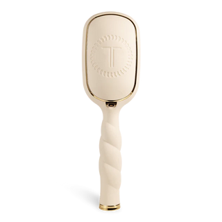 Beige paddle hairbrush with gold accents on a white background