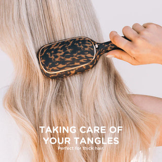 Person using a leopard print hairbrush on blonde hair with text 'Taking care of your tangles' and 'Perfect for thick hair'.