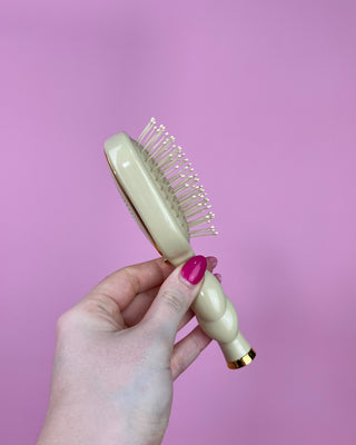 Hand holding a hairbrush against a pink background