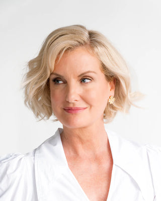 Woman with blonde hair wearing a white top against a light background