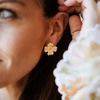 Close-up of a woman wearing a gold floral earring.
