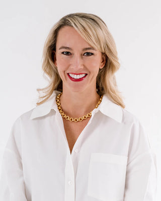 Woman wearing a white shirt and gold necklace on a white background