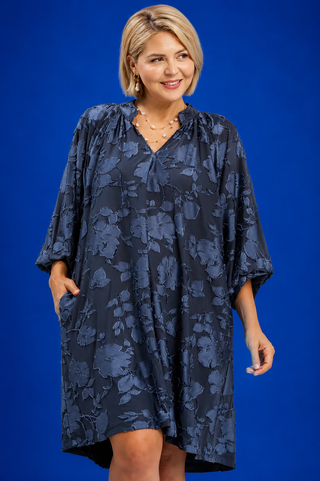 Woman wearing a blue floral dress against a blue background
