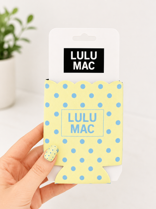 Yellow polka dot can cooler with 'LULU MAC' branding held by a hand.