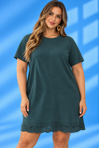 A woman modeling a dark teal green short-sleeve tunic dress with a scalloped eyelet hem