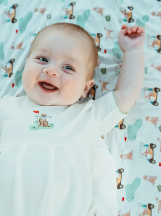 Baby lying on a patterned blanket with a smile