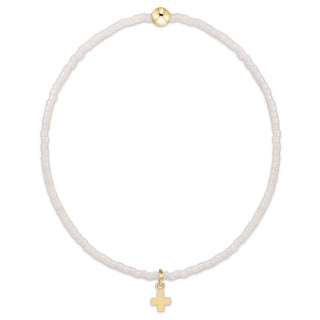 A delicate beaded necklace with small translucent white beads, featuring a small gold cross pendant and a gold accent bead