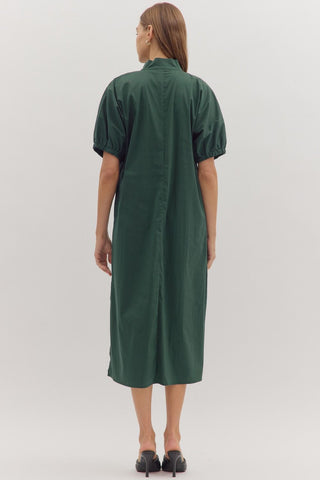 Person wearing a green dress standing against a white background