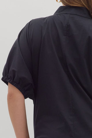 Black short-sleeve shirt worn by a person on a light gray background