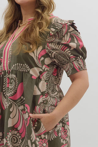 Woman wearing a patterned dress with pink and beige design on a plain background