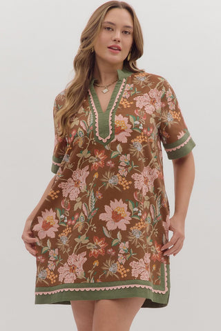 Woman wearing a floral dress with green trim on a white background