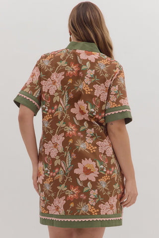 Woman wearing a floral dress with green trim on a white background